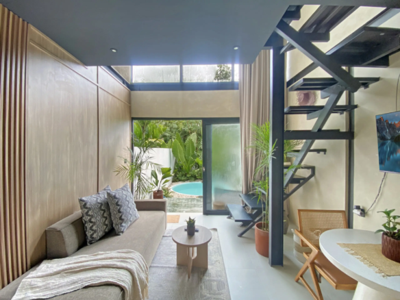 Modern living room with a black metal staircase, indoor plants, and a glass door opening to a small pool area outside.