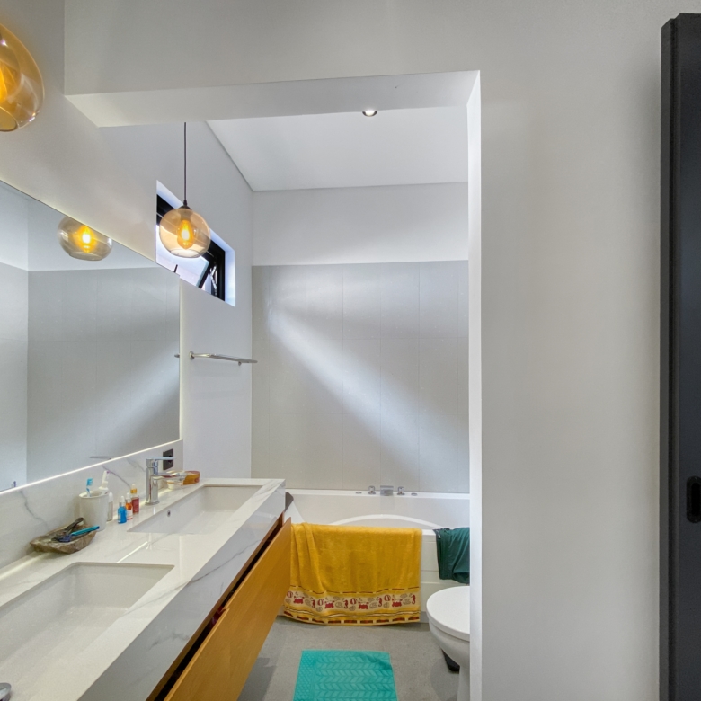 Modern bathroom with double white sink, marble countertop, and amber glass pendant lights.