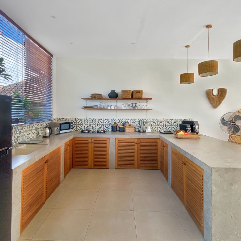 Bright kitchen with wooden cabinets, patterned tile backsplash, open shelves, and warm pendant lights.