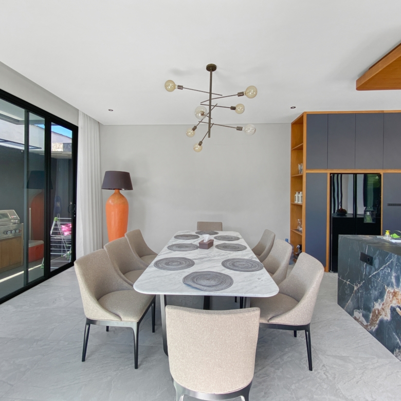 Modern kitchen-dining area with a marble table set for six, beige upholstered chairs, and a starburst chandelier overhead.