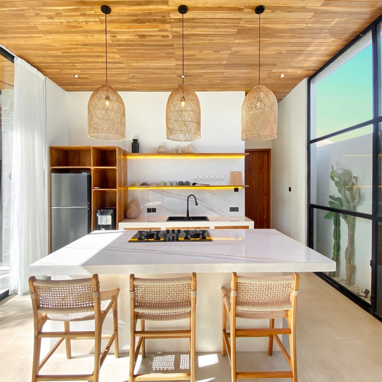 Open-plan kitchen with a white marble island, wooden cabinets, and three woven rattan pendant lights