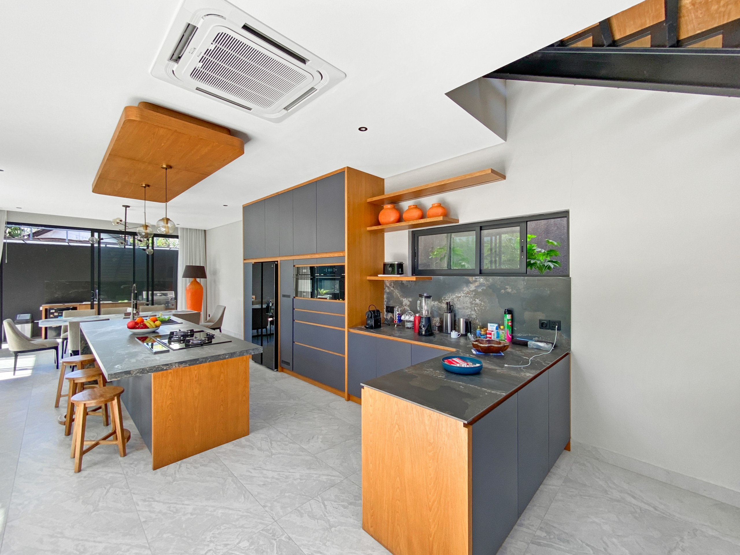 Open-concept kitchen with gray and wood cabinetry, an island, and a dining area.