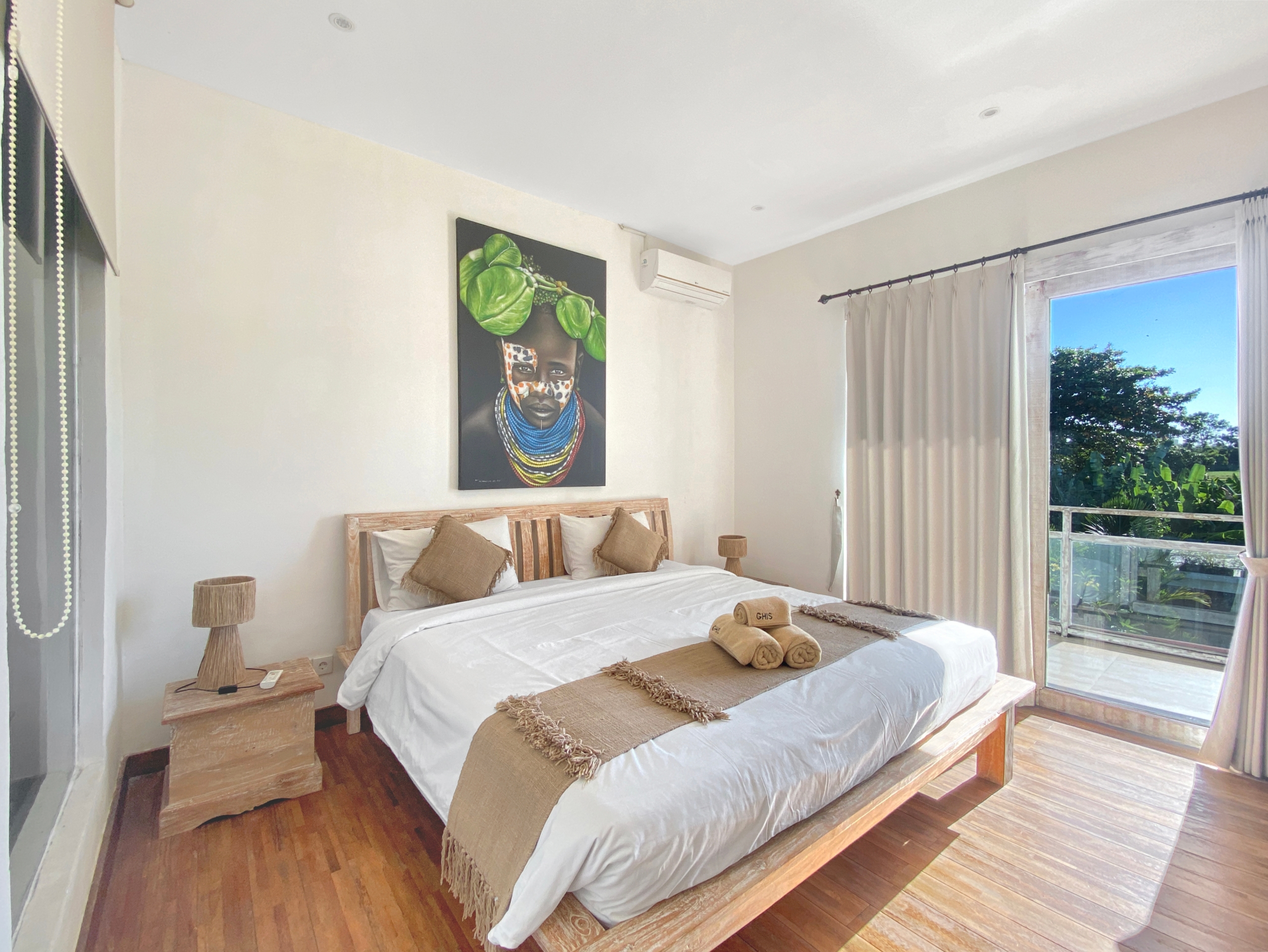 Bright bedroom with white bedding and a beige throw on a wooden bed, plus a bold wall art piece above the headboard.