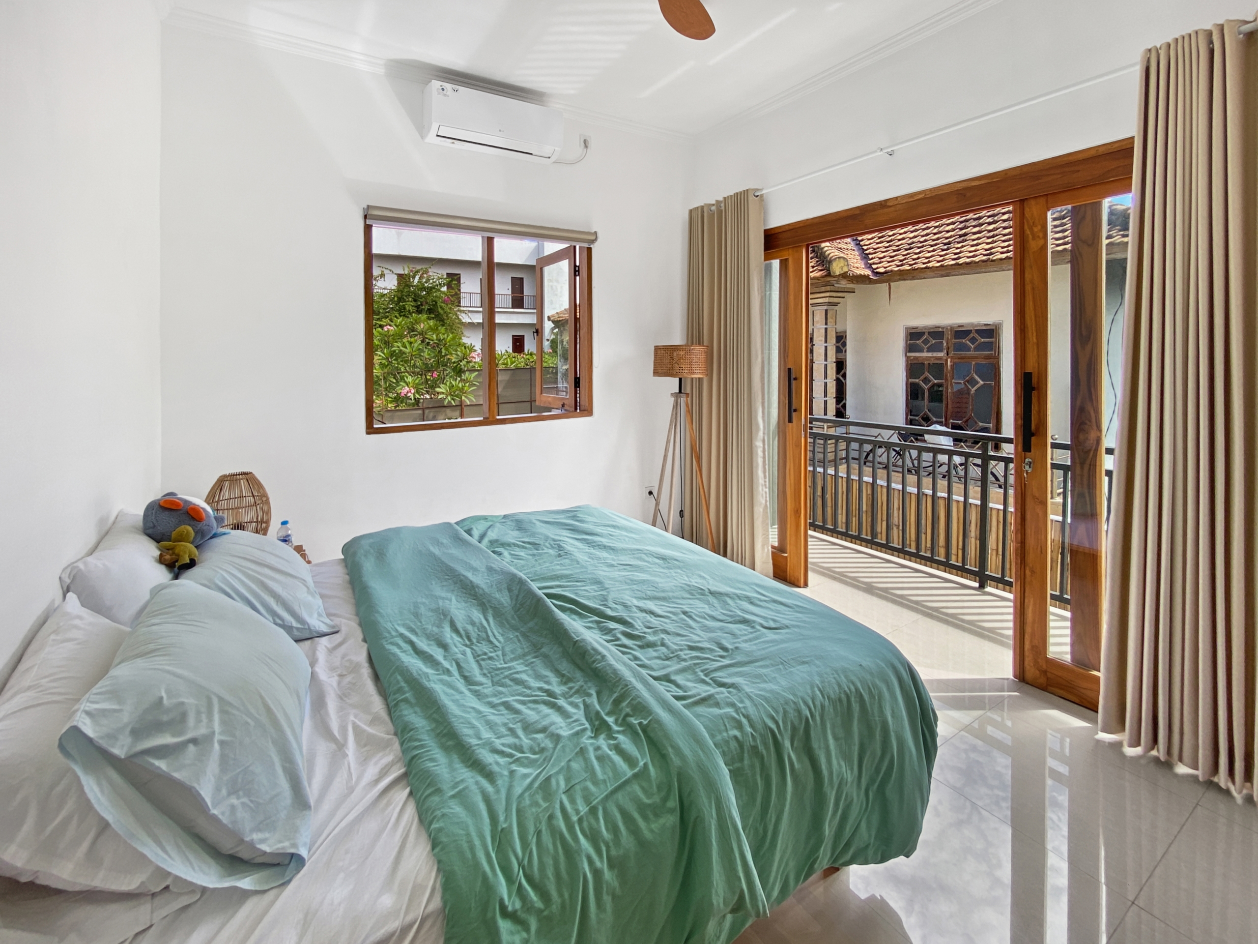 03ccd27b6b9b1008a2af9e50a9121e31dec211b6 Bright hotel-style bedroom with two neatly made beds, teal blankets, and a small stuffed toy on white sheets.