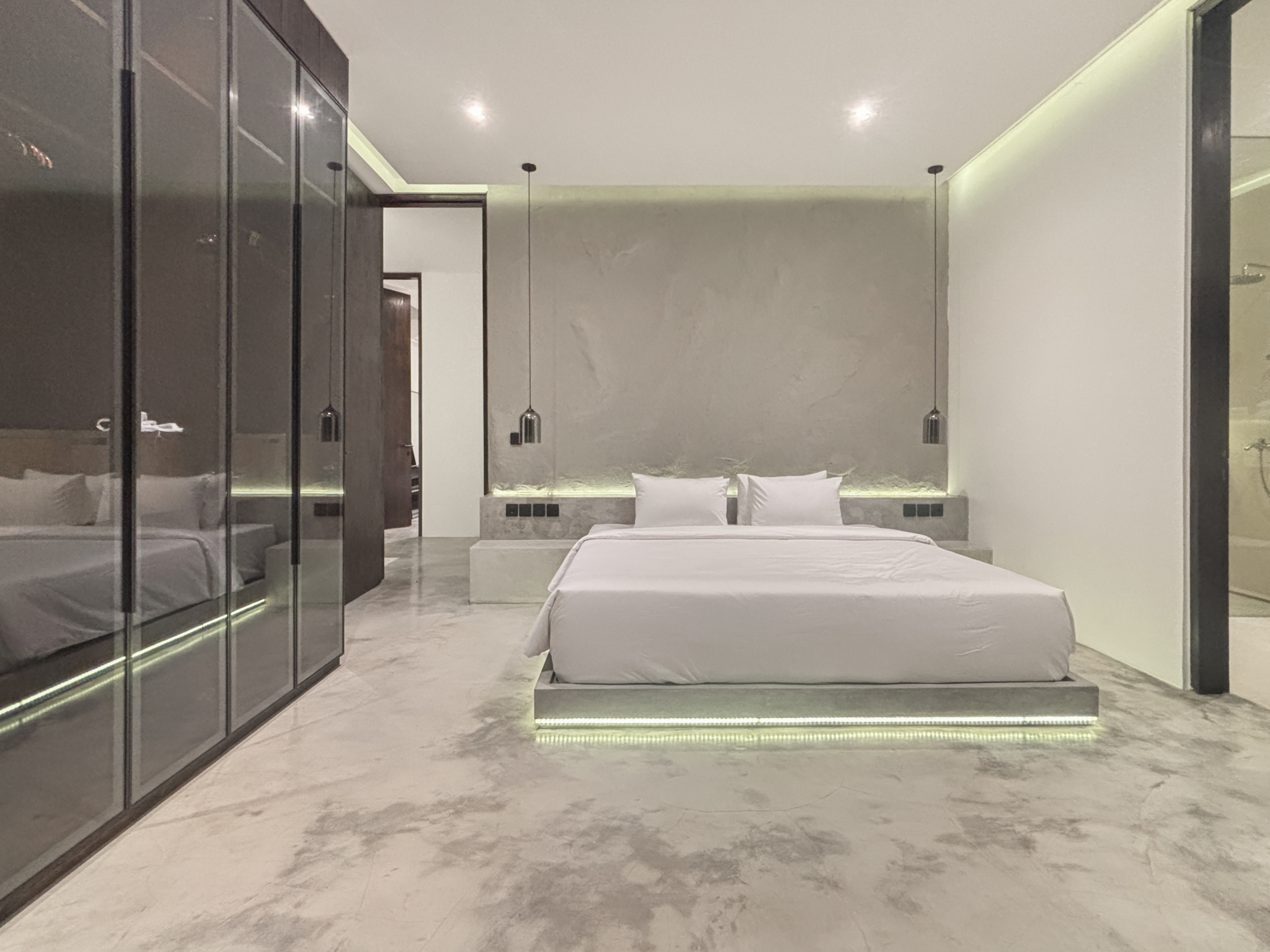 28527edca868c8735d1c8bae51c4f723b4e692f7_0923-6a05be07dcf7e Modern hotel bedroom with a low platform bed, white bedding, and glass-front wardrobes along the left wall.
