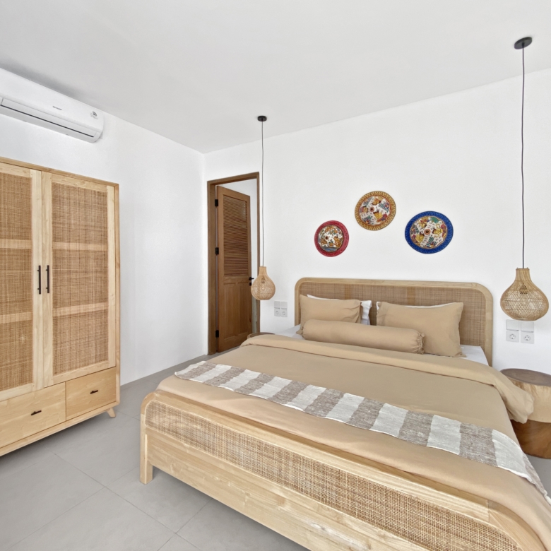 Bright hotel-style bedroom with two single beds, woven headboards, and wooden wardrobe units along a white wall.