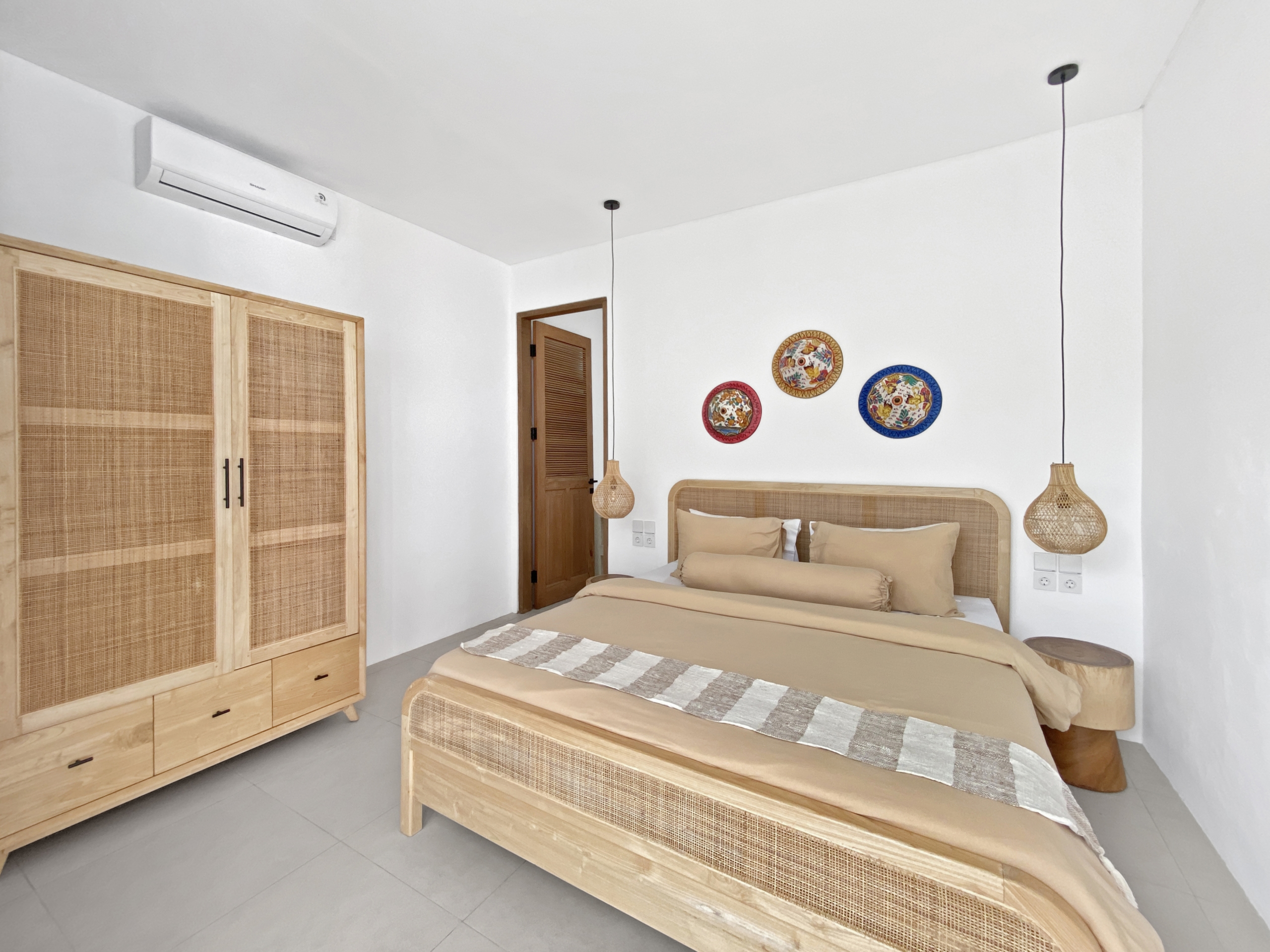 3577ced1b594def7b1595c828a6c63fa67e7a303_2297-68d5cfaff240c Bright hotel-style bedroom with two single beds, woven headboards, and wooden wardrobe units along a white wall.