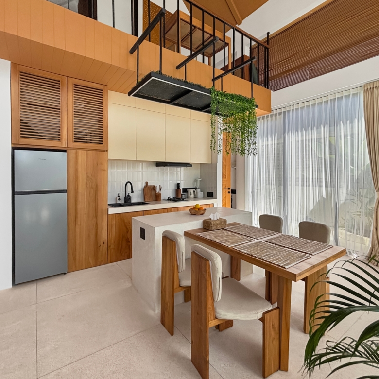 Modern kitchen with wooden cabinets, stainless fridge, and a white island; a hanging planter shelf with greenery over the island and a dining table nearby.