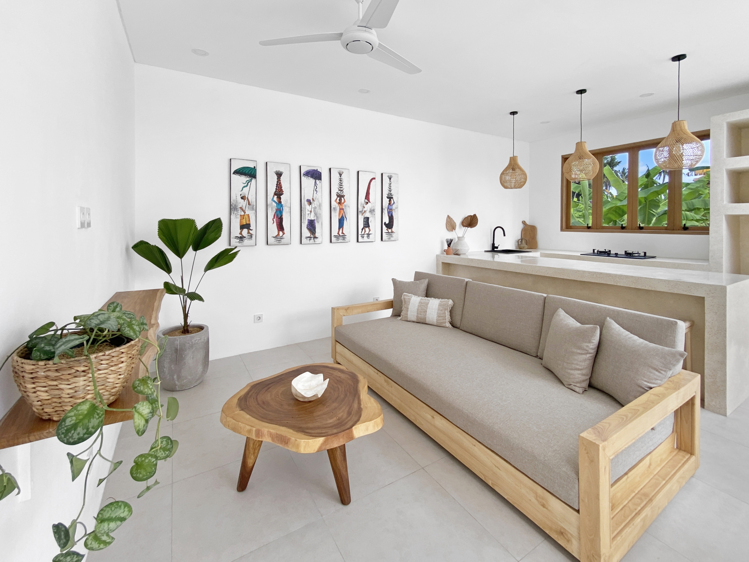 5a6170a92e3109892014b5044f871699836153cb_2315-68d5cfb26aafd Bright, minimalist living room with a beige sofa, live-edge wooden coffee tables, and potted plants; seven framed art pieces line a white wall.