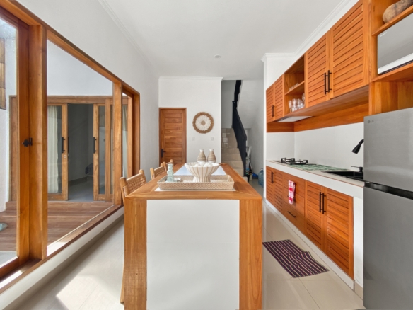 Bright kitchen and dining area with warm wooden cabinets, a central wooden dining table, and glass sliding doors.