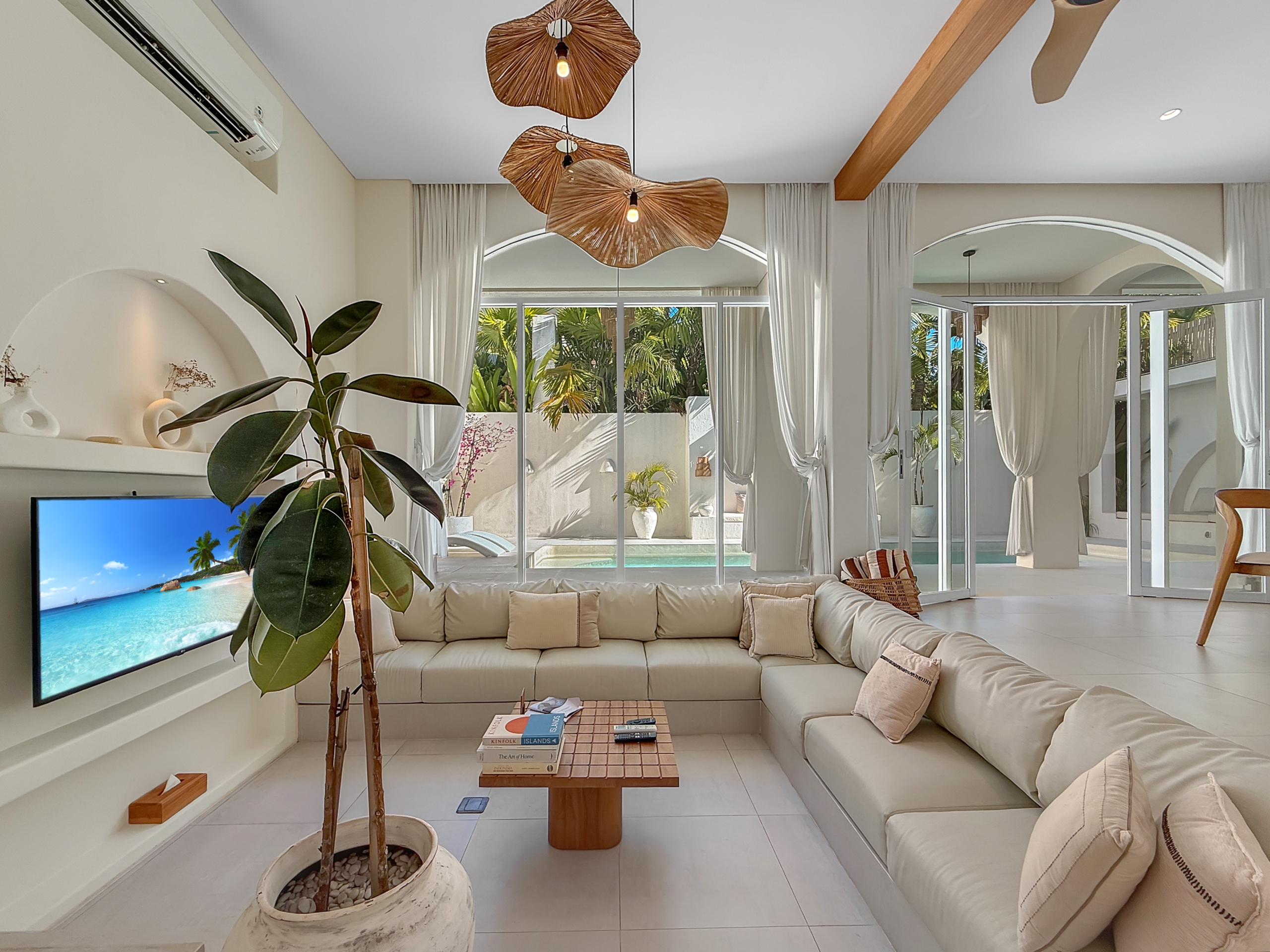 6dba9bf1b30d3a086d12288e5e7d5e935864f569 Bright living room with white sectional sofa, large glass doors to a sunny tropical courtyard and potted plant nearby.
