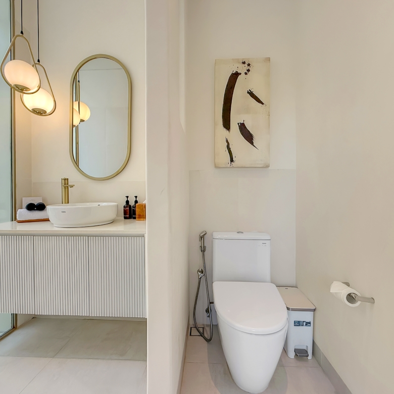 Modern bathroom with a glass shower, oval mirror, white vessel sink, and abstract wall art on the right wall.