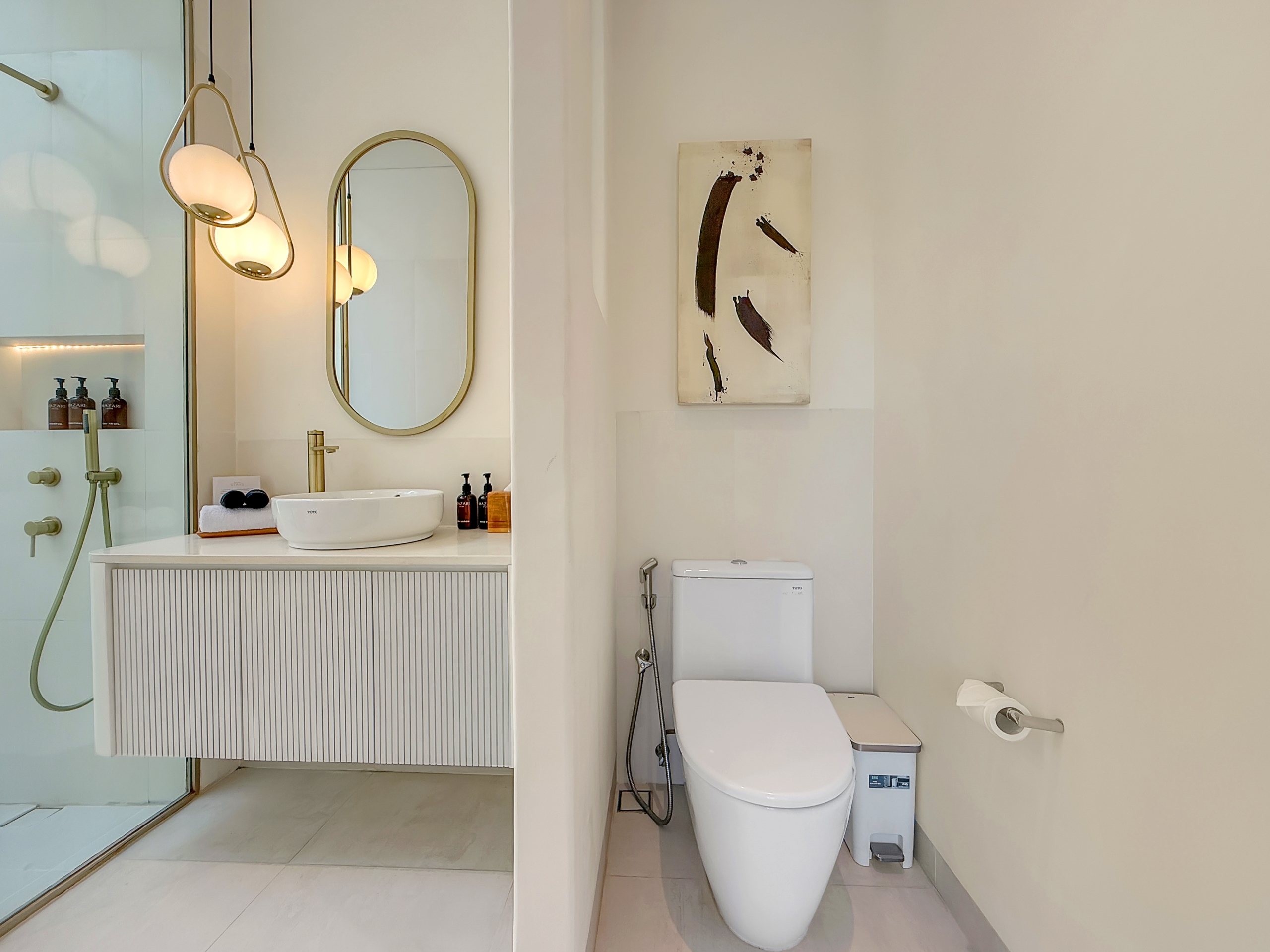 781789eacb56d015a3c076676595f6e457332cec Modern bathroom with a glass shower, oval mirror, white vessel sink, and abstract wall art on the right wall.