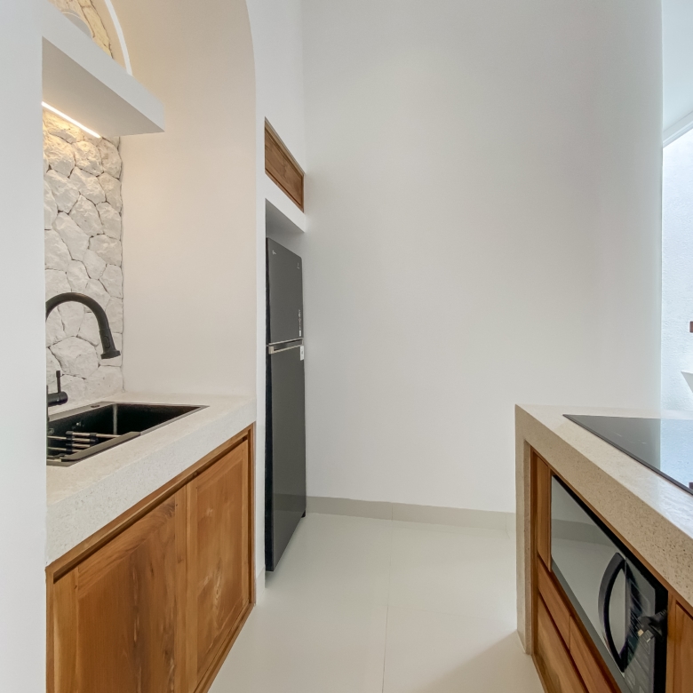 Modern U-shaped kitchen with white walls, light countertops, wooden lower cabinets, and a stone-tile backsplash around the sink area; black faucet over a double sink.