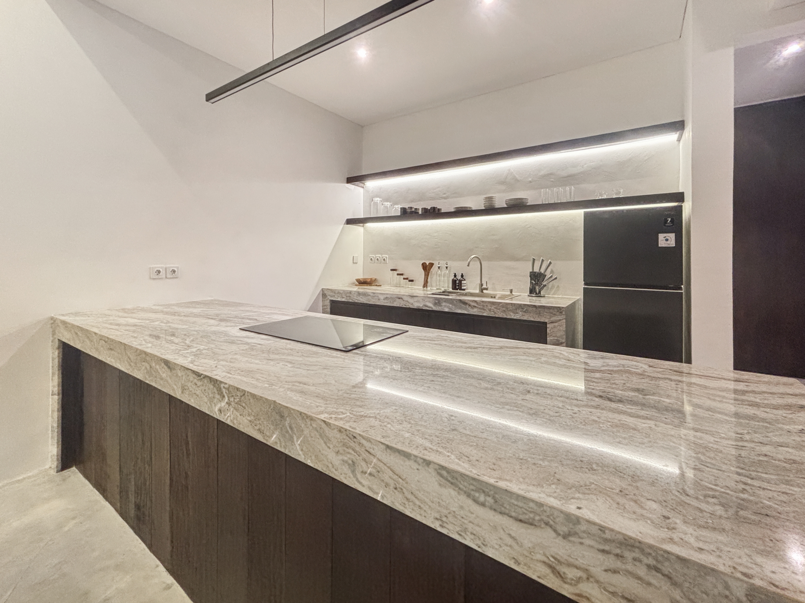 880b8736e21a0e5d93aacd32d29a70ac96812a4c_0947-6a05be06efd40 Modern kitchen with marble countertops, open shelves holding dishes, and a stainless steel oven against white walls.