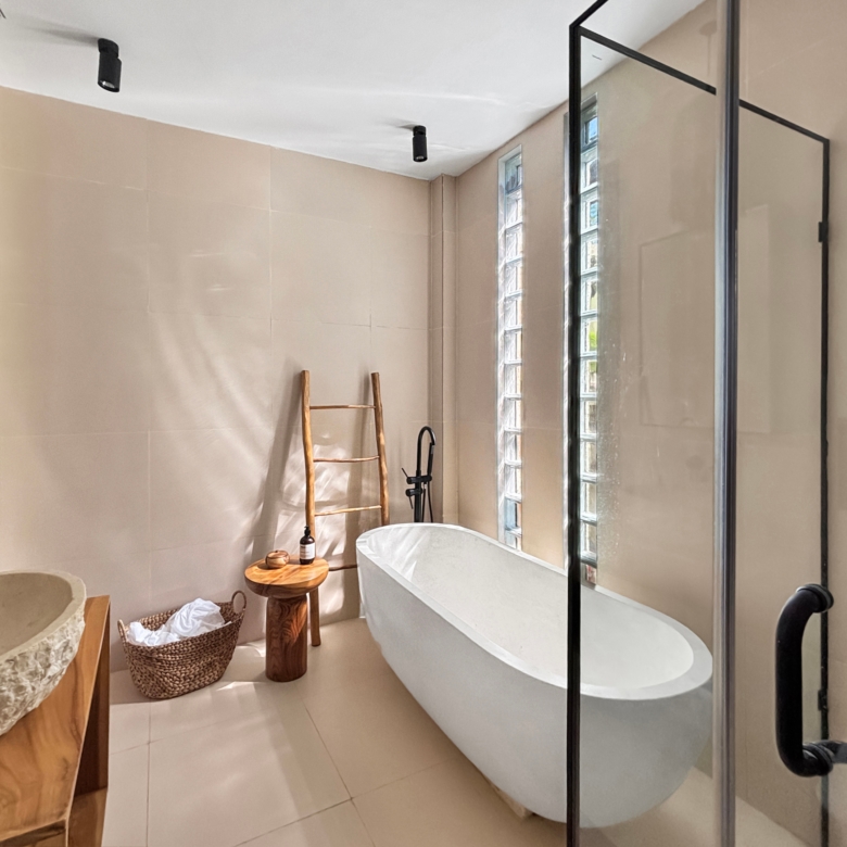 Spa-inspired bathroom with a white freestanding tub next to a glass-block window and a glass shower enclosure framed in black metal.