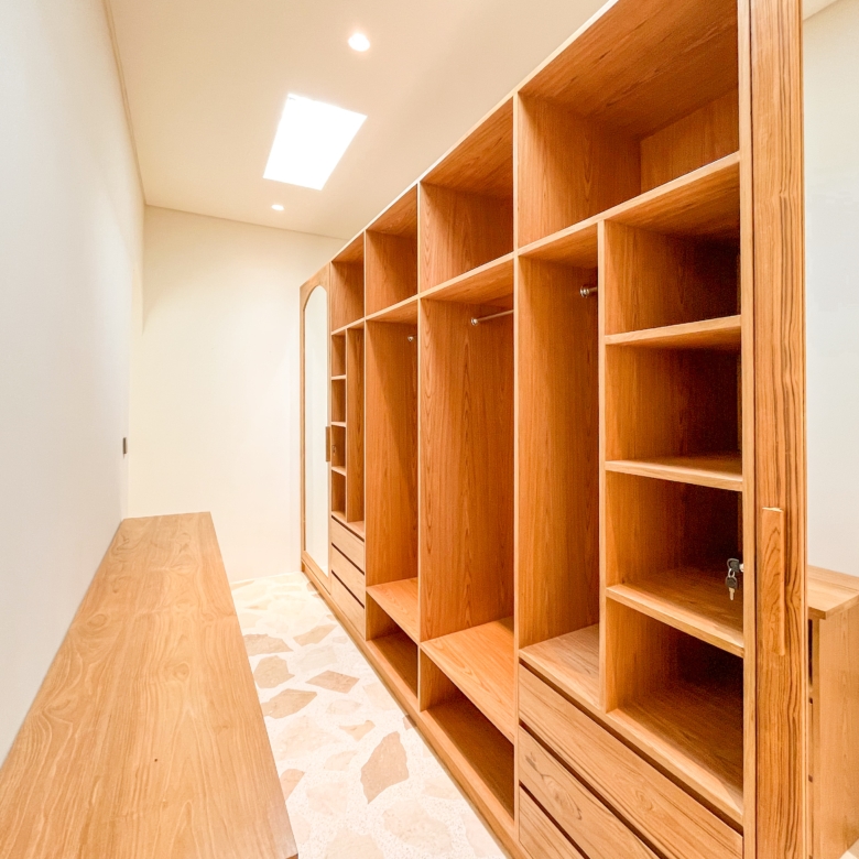 Wooden locker units with open cubbies and drawers lining a narrow bright room.