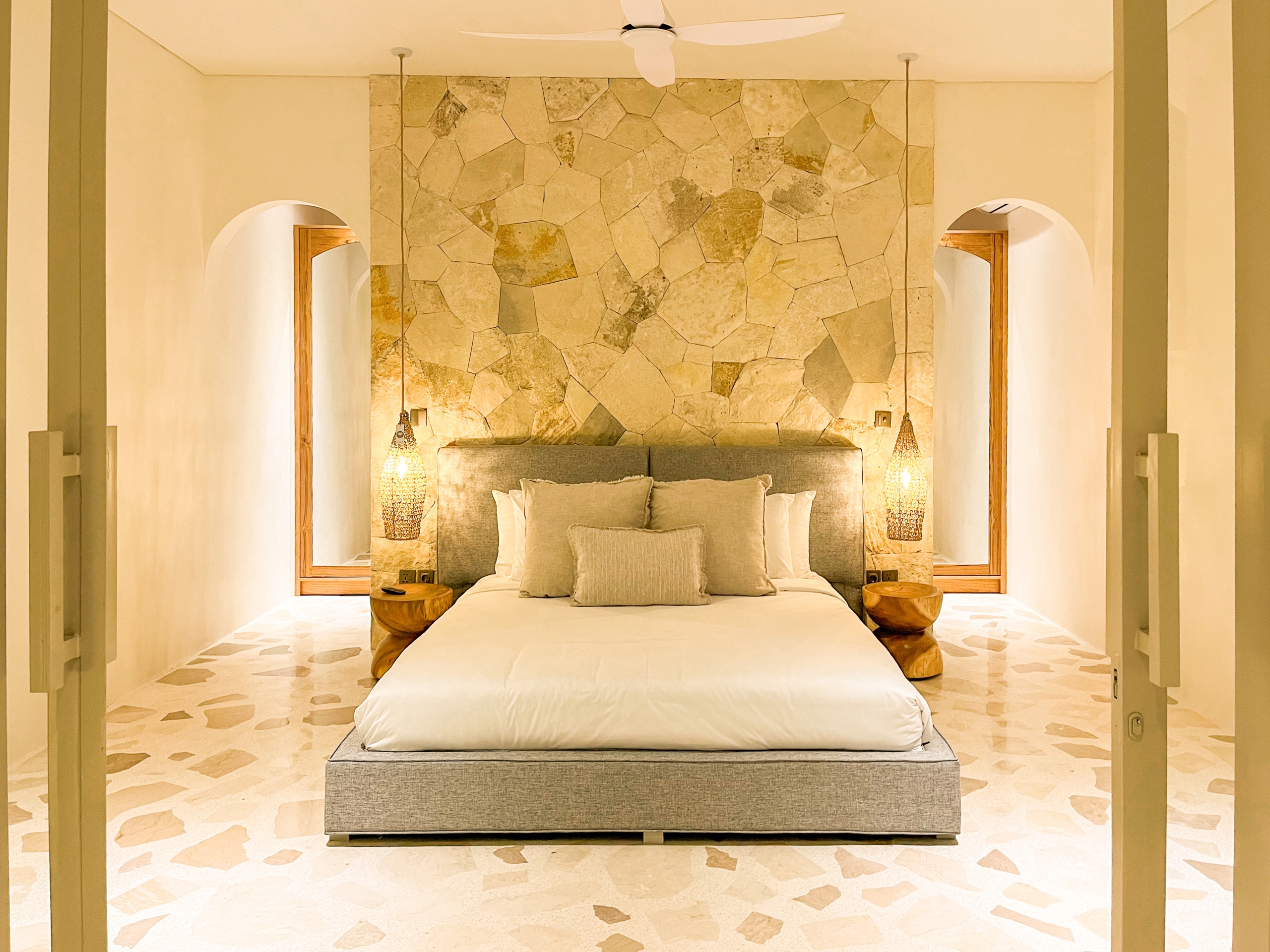 IMG_0678_4625-6a38c7b4e025f Hotel-style bedroom with a stone feature wall behind a low-profile bed and pendant lights on each side