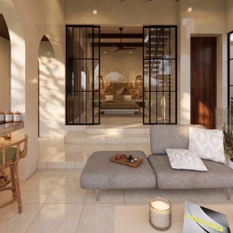 Open-plan living room with a gray sectional, neutral decor, and a glass-walled bedroom suite in the background, bathed in warm natural light.