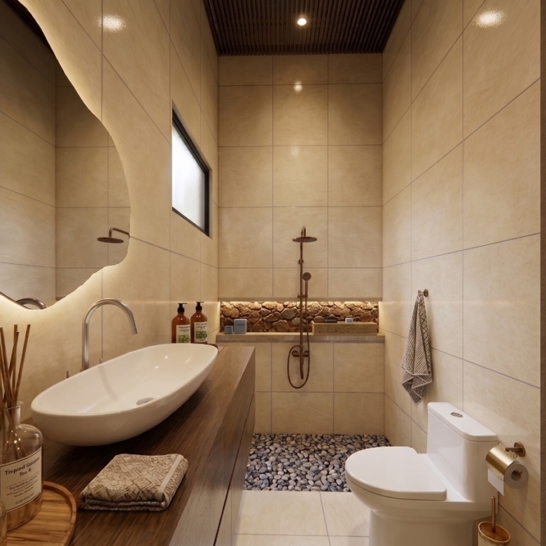 Modern beige-tiled bathroom with a large irregular backlit mirror, white vessel sink on a wooden counter, and a pebble shower floor.