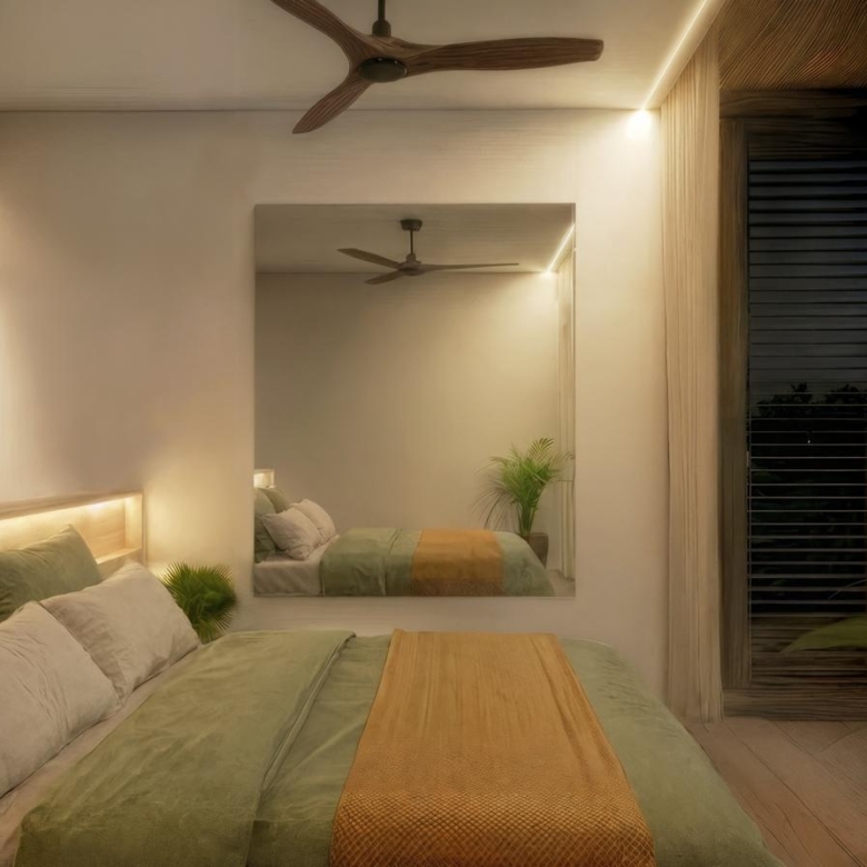 Hotel-style bedroom with a king bed, green and beige bedding, and warm bedside lighting; a large wall mirror reflects the room.