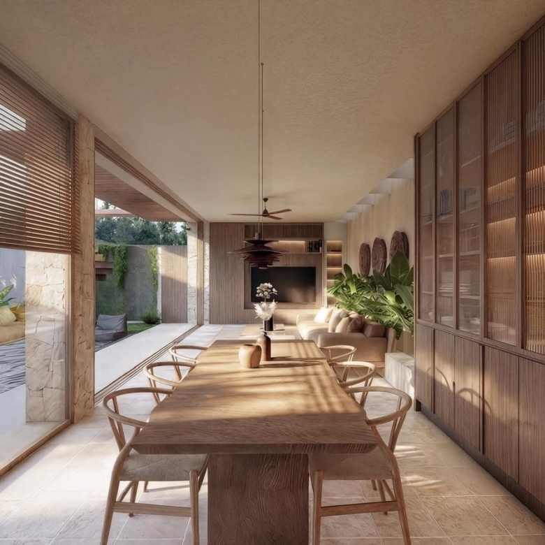 Open-plan dining room with a long wooden table and six wooden chairs, flanked by built-in timber cabinets, opening to a patio and living area with plants and a ceiling fan.