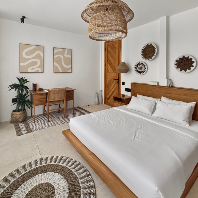 Bedroom with two twin beds and natural wood furniture, round woven rugs, and wicker pendant lights creating a calm, coastal vibe.
