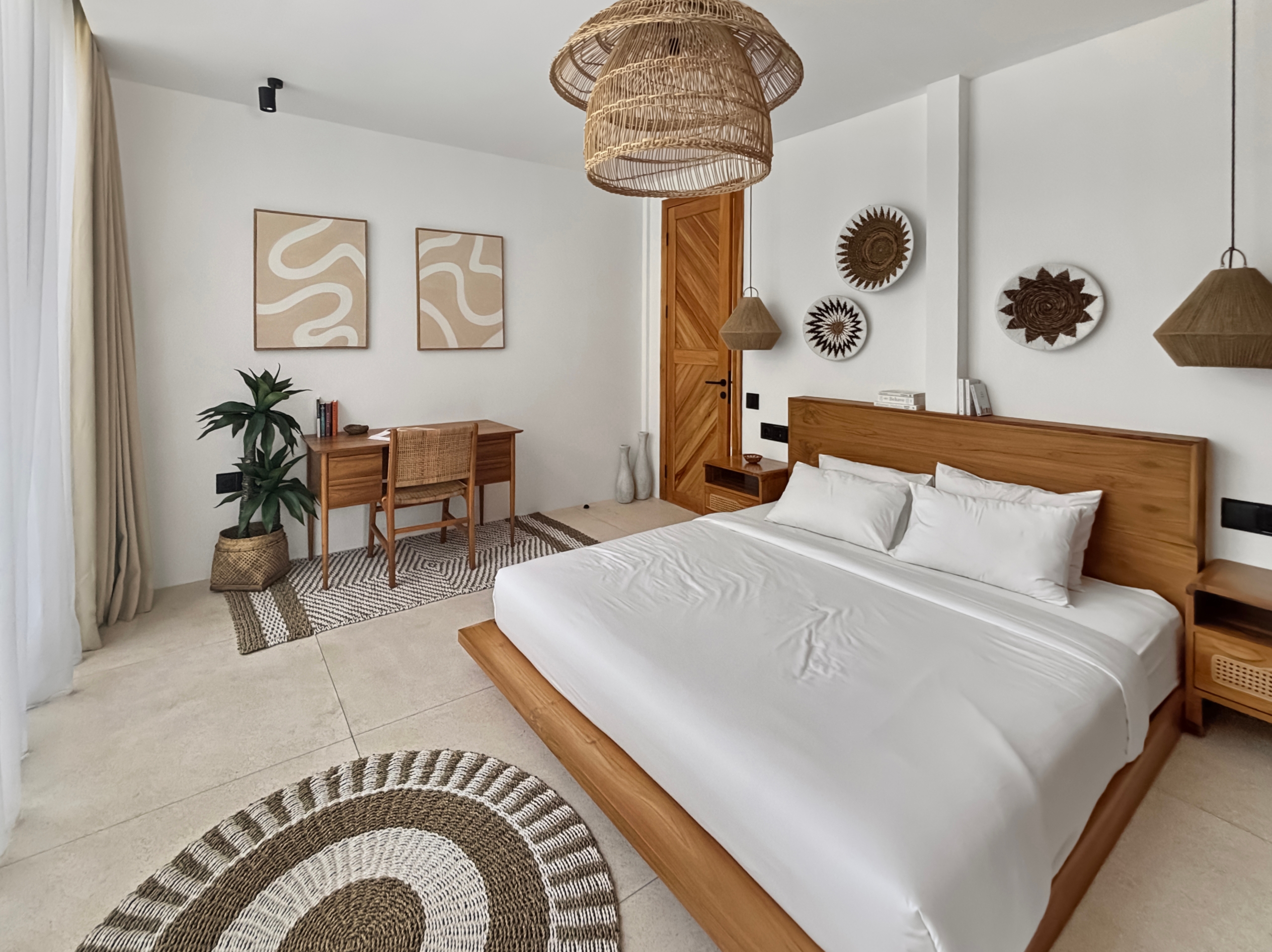 a739324953394102fa2dc29e82d7d9070a47a867 Bedroom with two twin beds and natural wood furniture, round woven rugs, and wicker pendant lights creating a calm, coastal vibe.