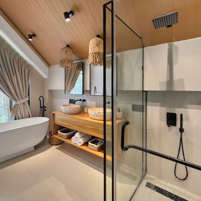 Spa-like bathroom featuring a freestanding oval tub, wooden vanity, and glass-enclosed shower with black fixtures and woven pendant lights.