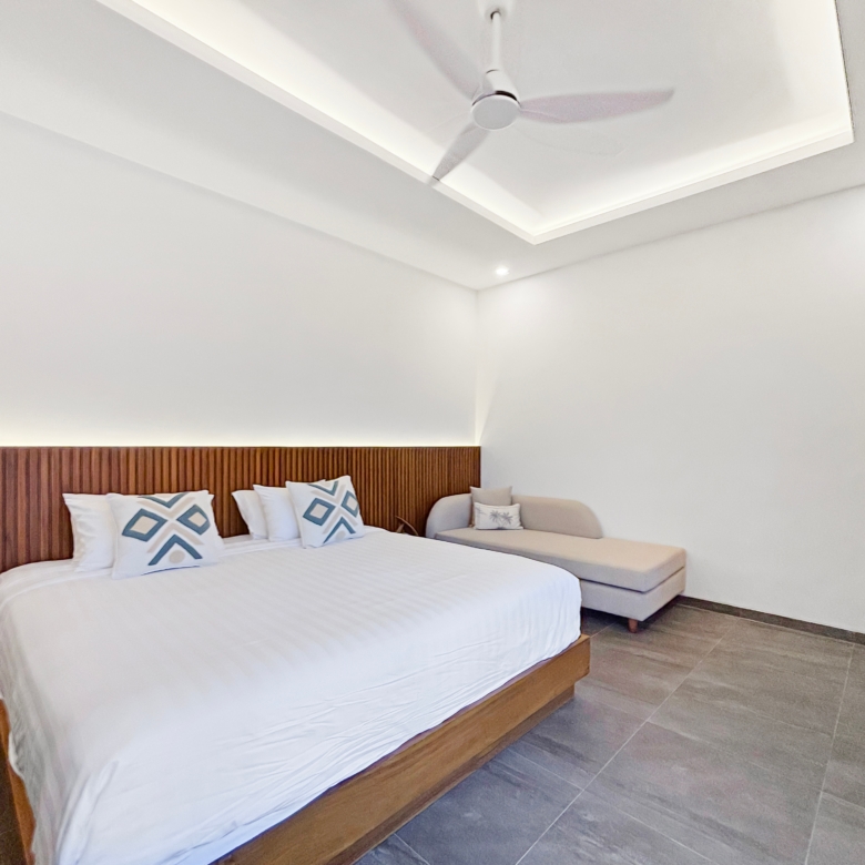 King bed with white linens and a tall wooden slatted headboard in a bright hotel room in the background of the image.