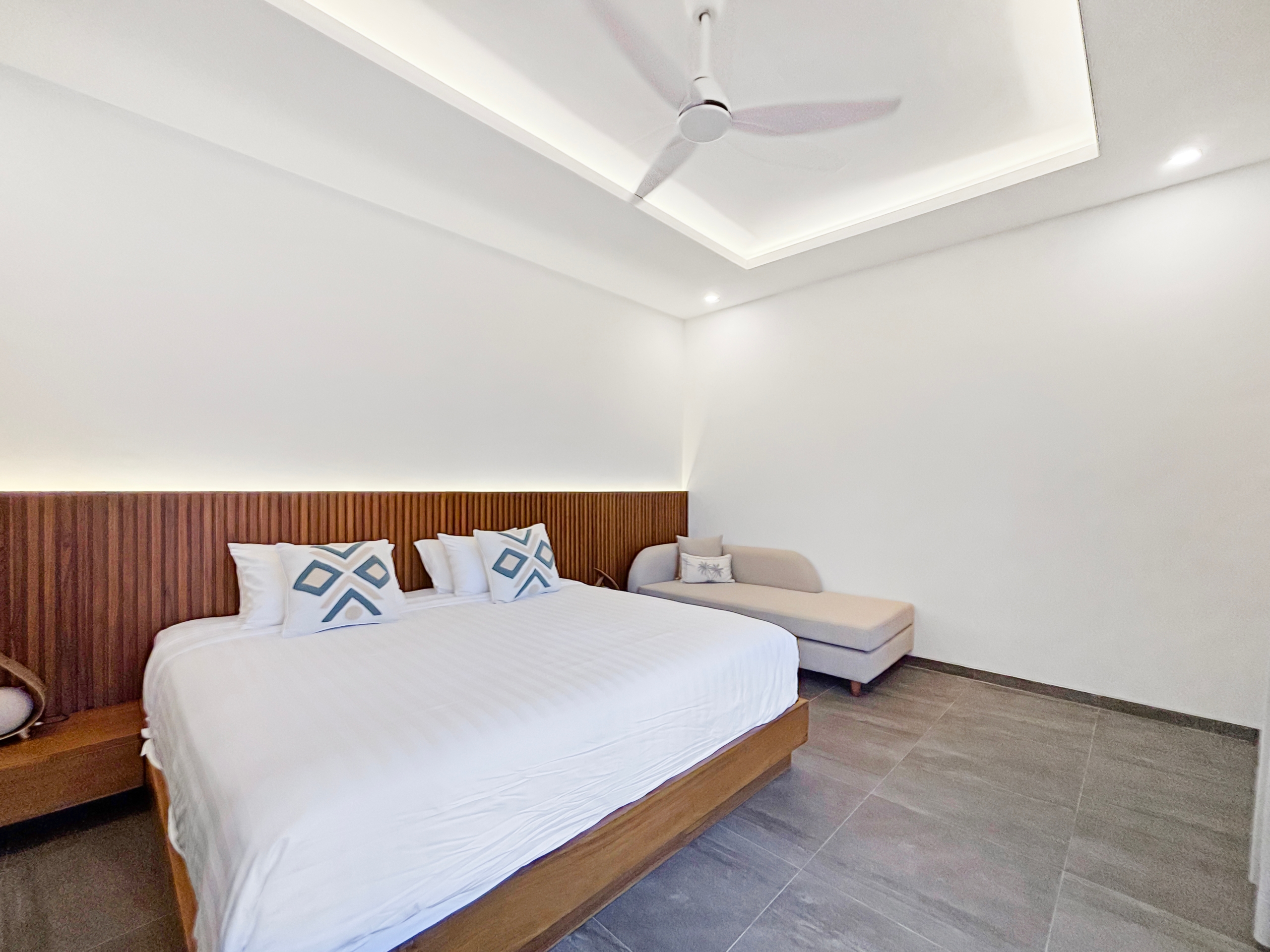 c6eade9da211a3083cd906a1789195065a06dc7e King bed with white linens and a tall wooden slatted headboard in a bright hotel room in the background of the image.