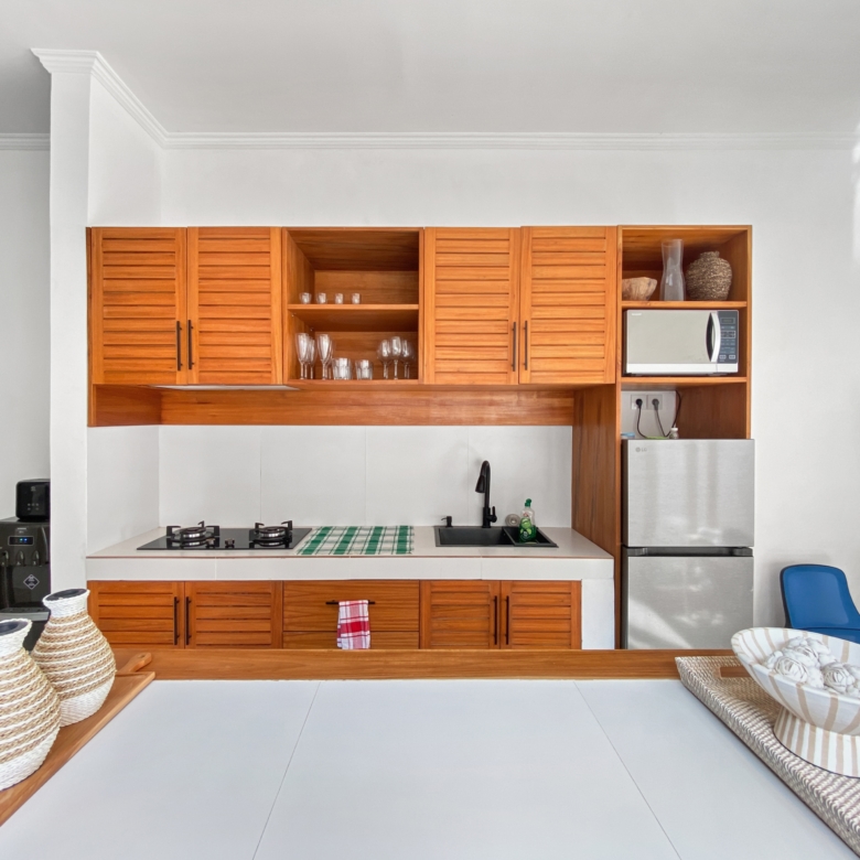 Modern kitchen with warm wooden cabinets, white countertops, a gas stove, and a stainless steel sink.