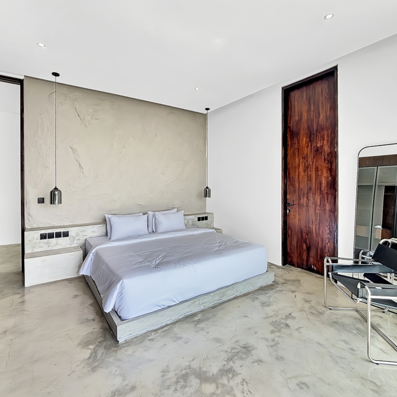 Modern hotel-style bedroom with marble floor, low platform bed and two pendant lights on textured wall.