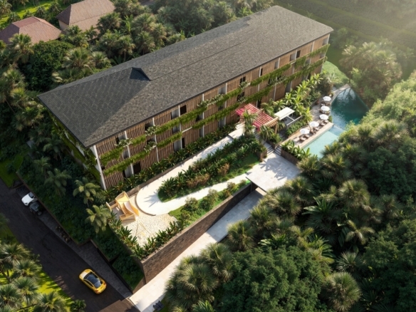 Aerial view of a tropical resort with a long wooden building, lush greenery, and a pool deck with umbrellas.