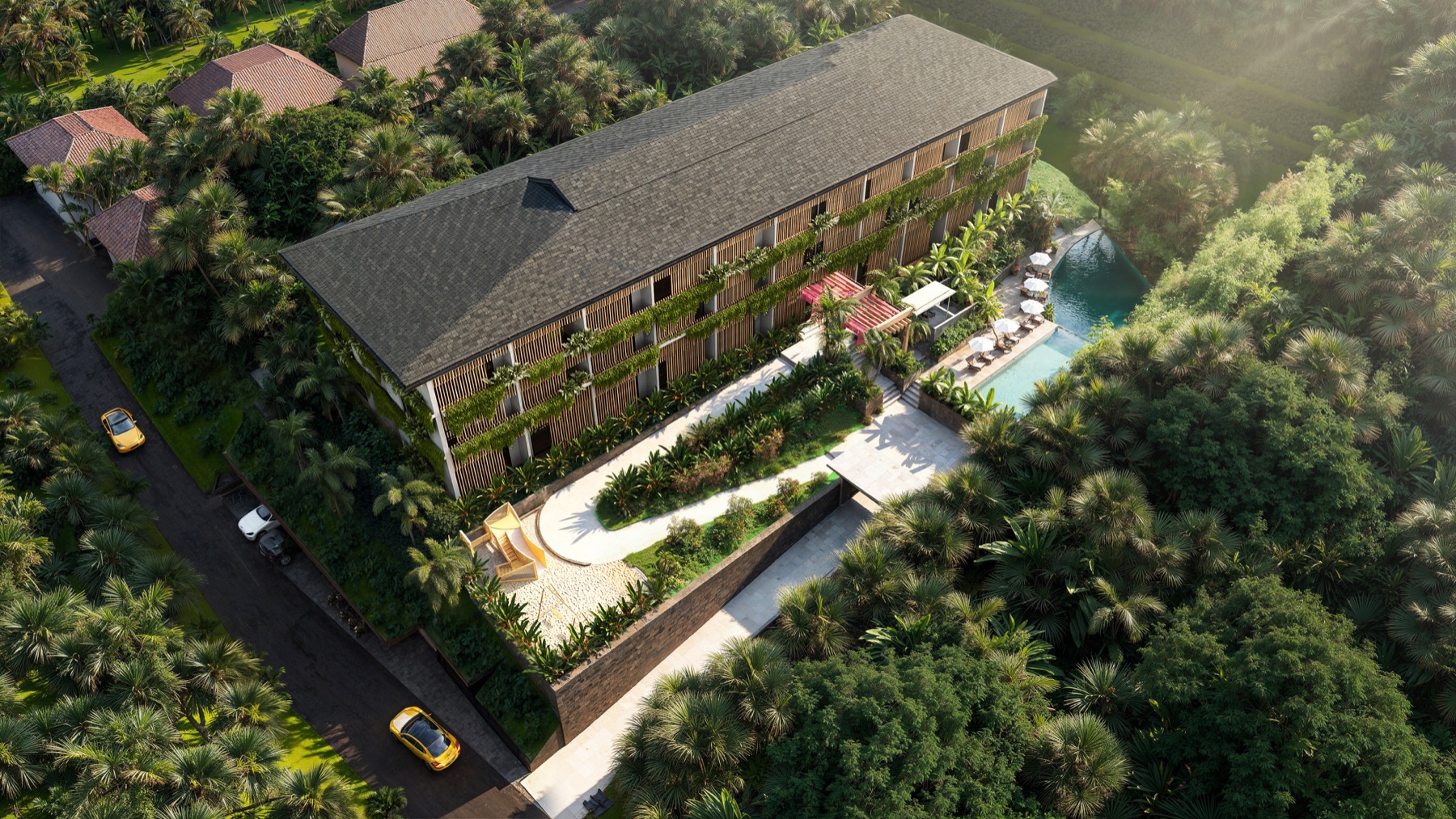 Aerial view of a tropical resort with a long wooden building, lush greenery, and a pool deck with umbrellas.