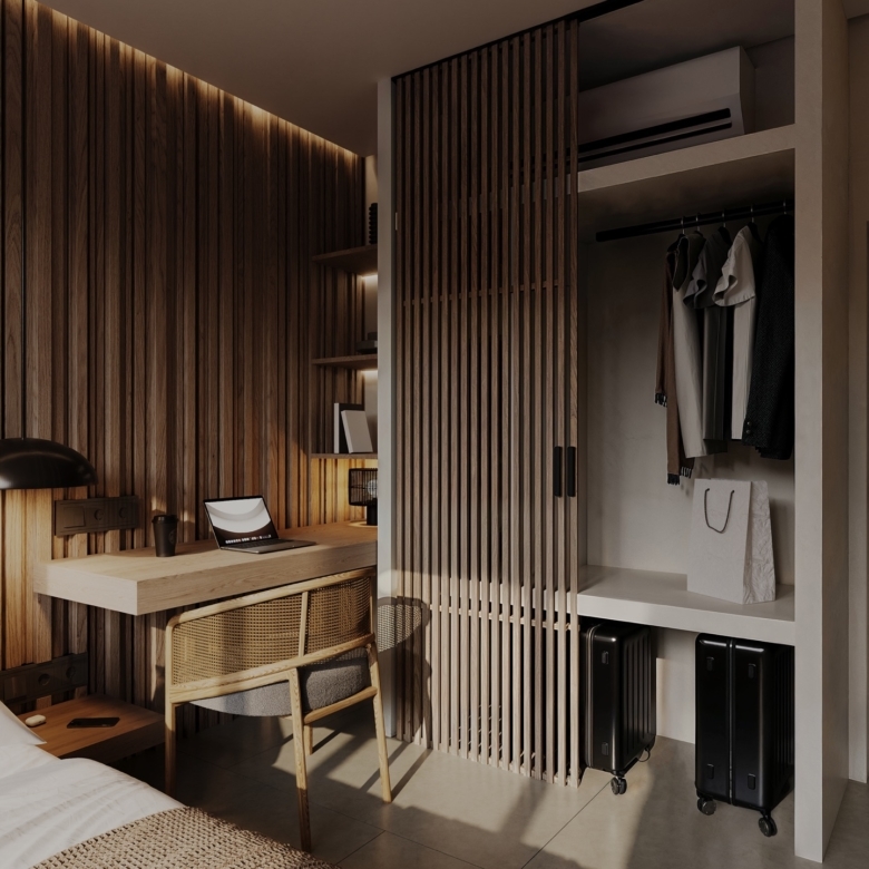 Modern bedroom with a wooden slat wall, desk and laptop, and an open wardrobe with hanging clothes and luggage below.
