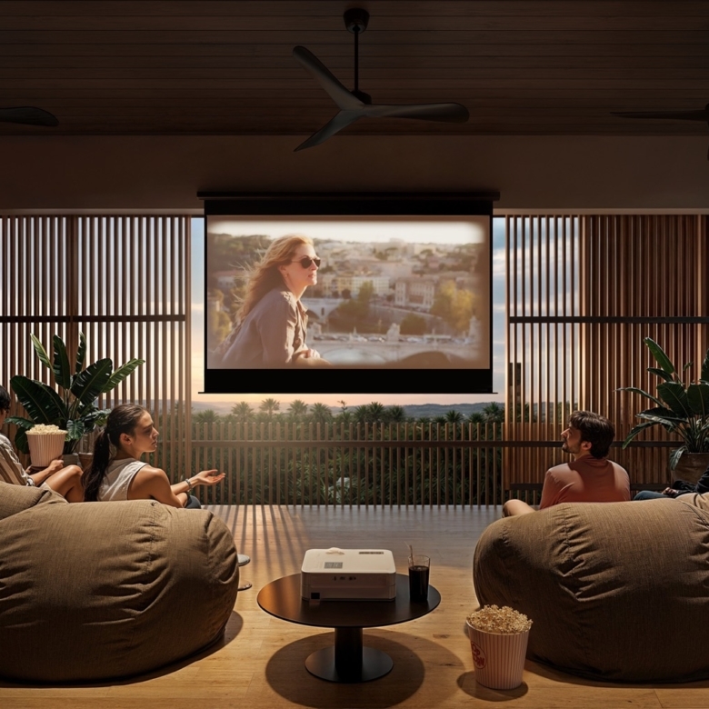 Four friends lounge on bean bags in a modern open living area, watching a movie projected on a screen as sunset lights the scene.